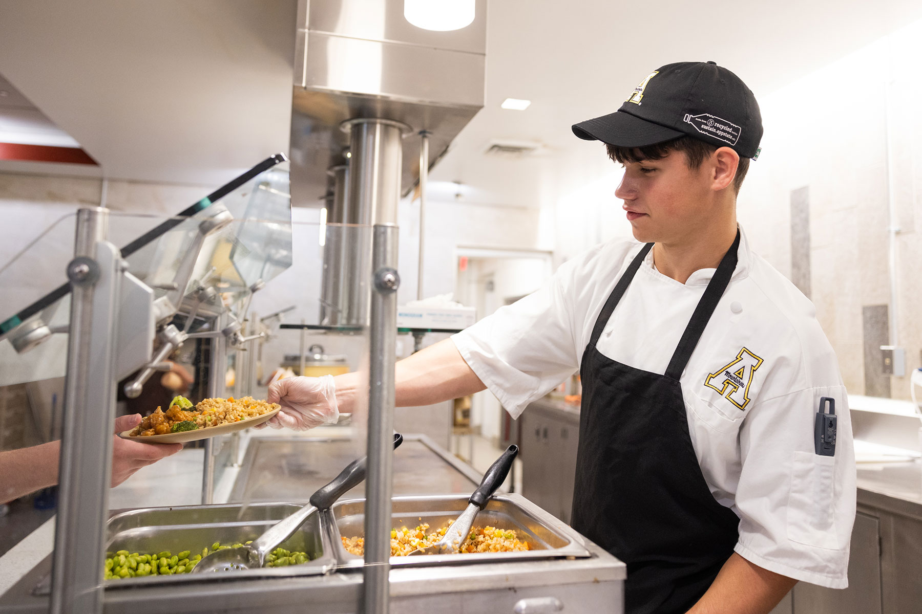 A professional food service line with stainless steel equipment and food containers.