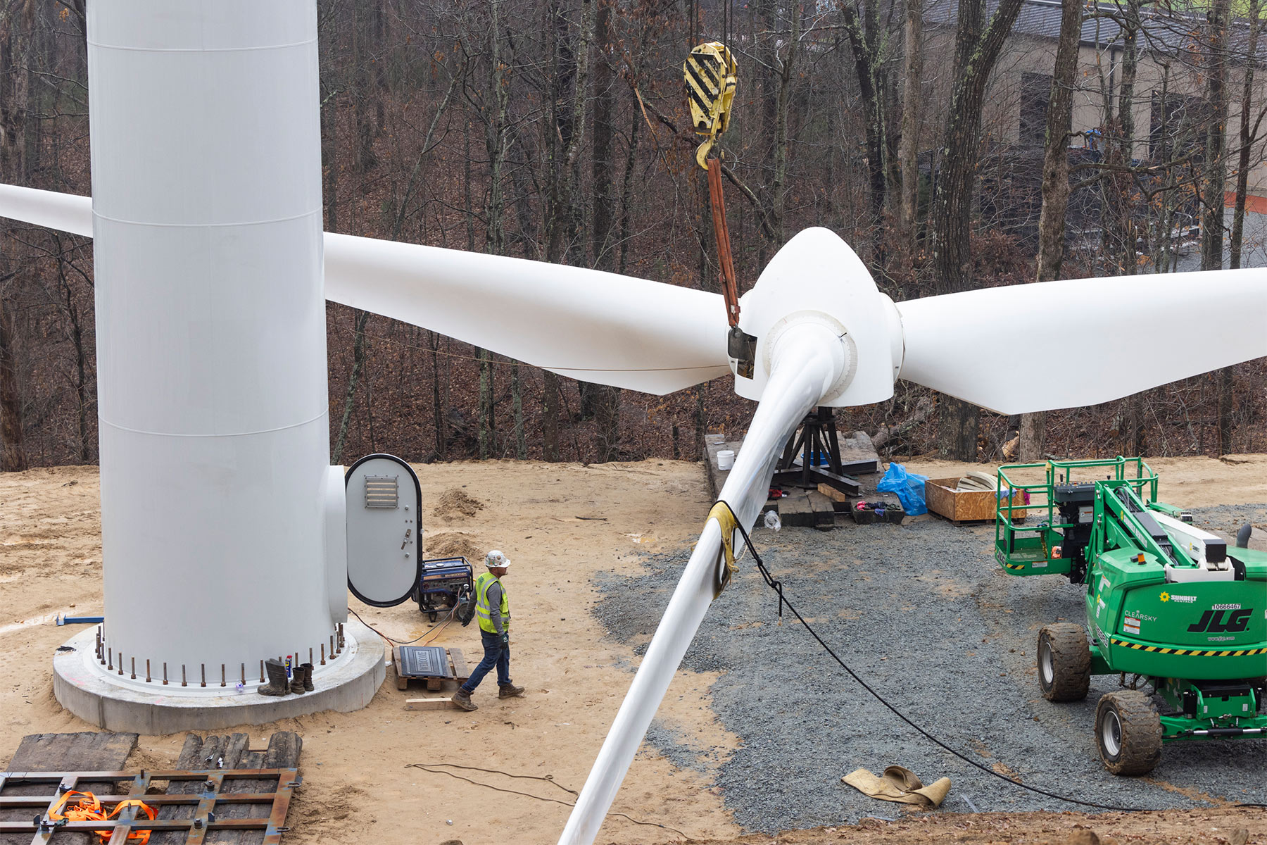 A worker, left, is pictured next to the rotor blades of one of two new wind turbines that are being installed