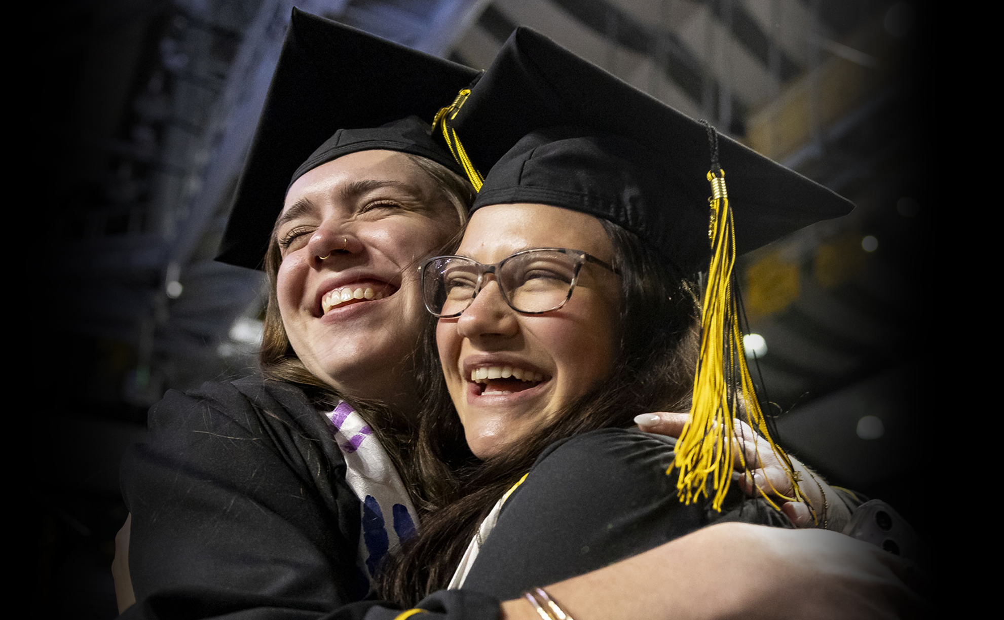 Two graduates in cap and gown celebrating.