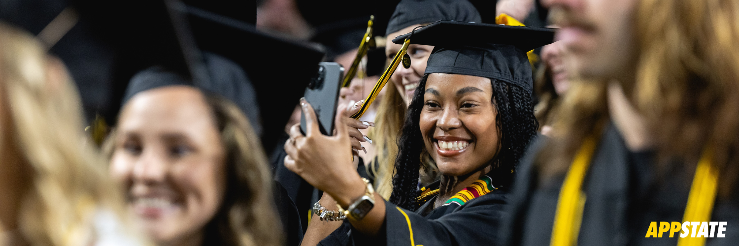 Graduate taking selfies at a commencement ceremony.