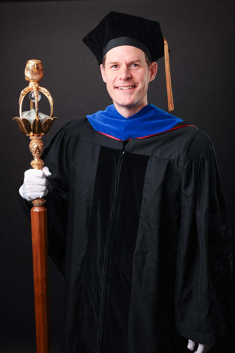 Dr. Justin Cox holding the university mace.